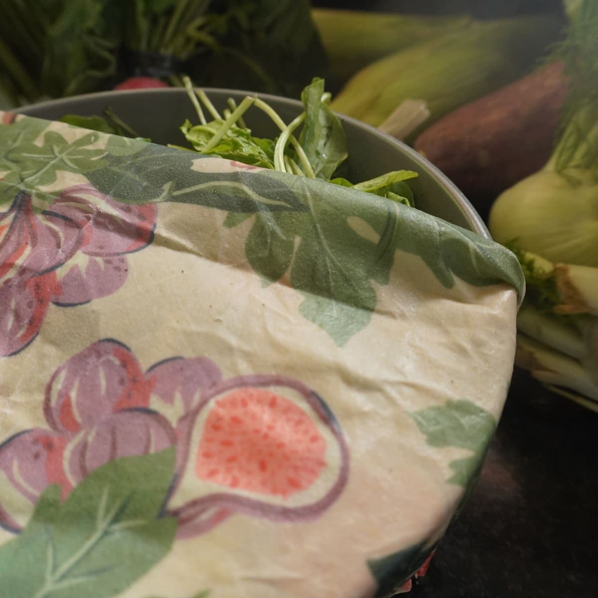Wrap con patrón de higos tapando un recipiente con hojas verdes